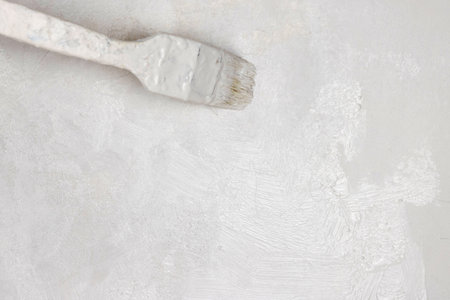 Closeup of a paintbrush applying white paint on a wall, perfect for home renovation and diy projects to give interiors a fresh, clean, and modern look. Minimalistic, bright decor. Copy space.の写真素材