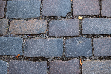 Closeup of weathered granite cobblestone pavement. Detailed image of old stone paving blocks. Street road surface pattern. Rustic charm of cobblestone pathways.の写真素材