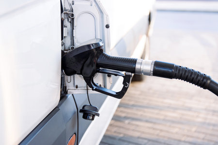 Closeup of a fuel nozzle in the car tank. Process of refilling a white transporter bus at a gas station. Refueling pistol inserted into a vehicle at a gas station. Copyspaceの写真素材