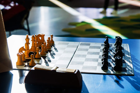 Chessboard with wooden pieces  on a blue table, arranged for a new game on a tournament board, symbolizing intelligence, competition, and classic board game tactics. Selective focusの写真素材