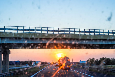 Highway and bridge at sunset through a dirty windshield, emphasizing road safety and the challenges...