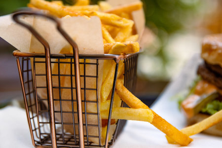 Closeup of a restaurant table with classic fast food meal. Burger with beef patty, fresh lettuce and...