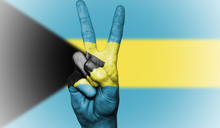 Hand showing the international symbol for peace, decorated in the national colors of The Bahamasの写真素材
