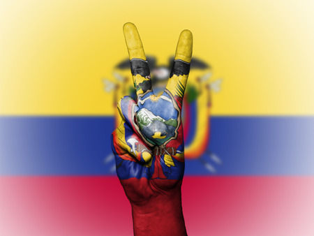 Hand showing the international symbol for peace, decorated in the national colors of Ecuadorの写真素材
