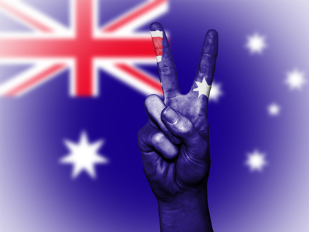 Hand showing the international symbol for peace, decorated in the national colors of Australiaの写真素材