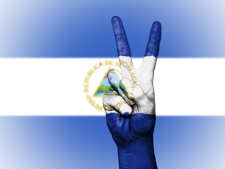 Hand showing the international symbol for peace, decorated in the national colors of Nicaraguaの写真素材