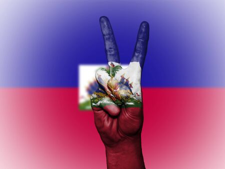 Hand showing the international symbol for peace, decorated in the national colors of Haitiの写真素材