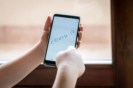 Coronavirus, Covid-19, hand-drawn text by a child on a smartphone display