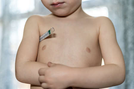 Sad and sick child measuring fever with a thermometer.のeditorial素材