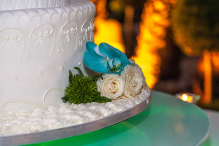 Decoration of a wedding cake with white roses and colorful flowers, wedding event.の写真素材