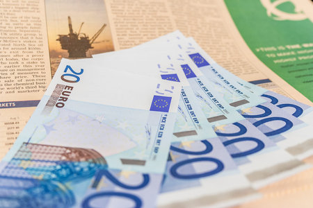 Many Euro banknotes of european currency on trading newspaper with oil well pictureのeditorial素材