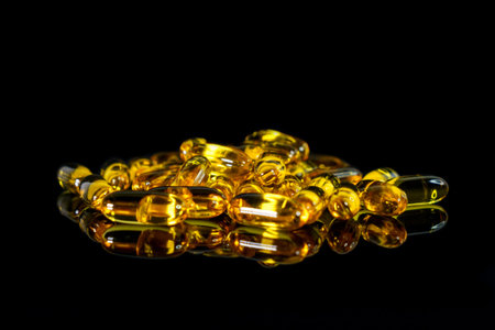 Fish oil capsules on a black background. Theme of health
