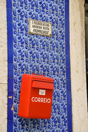 Red post box on the wall full of tiles
