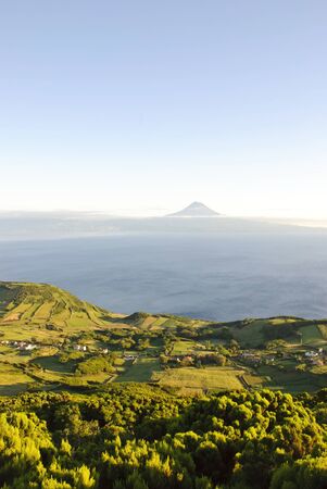 Green meadows of Sao Jorge island with Pico mountain behind, Azores, Portugalの写真素材