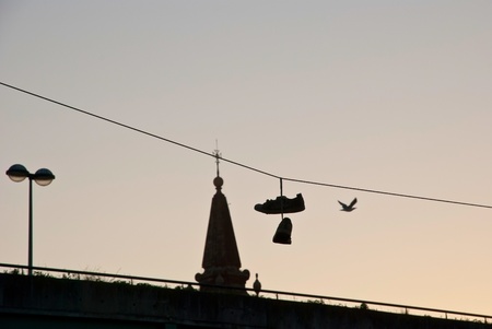 Silhouette of shoes hanging on the cable over the cityの写真素材