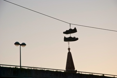 Silhouette of shoes hanging on the cable over the cityの写真素材