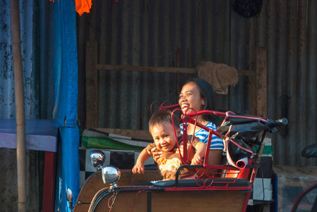 YOGYAKARTA, INDONESIA - SEPTEMBER 15: Indonesian woman and her son enjoying a ride in rickshaw in Yogyakarta, Indonesia on September 15, 2014.のeditorial素材