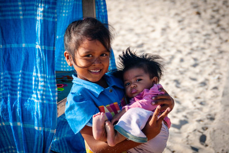 BALI, INDONESIA - SEPTEMBER 25: Yound unidentified balinese girl aged around 5 holding her brother aged around 9 months. Balinese people are native to Indonesian island of Bli. In Bali on September 25, 2014.のeditorial素材