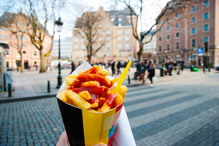 Holding trypical belgian fries in hand in the streets of Brusselsの写真素材