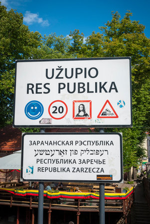 Lithuanian road sign with text against of green tree and sky to enter Uzupis autonomous communityのeditorial素材