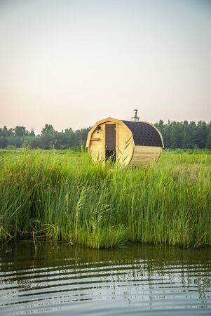 Wooden outdoor sauna by the lake in summer sunsetの写真素材