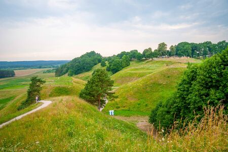 View on unrecognizable people walking footpath on green hills. Hill forts in Kernave, old Lithuanian capitalの写真素材