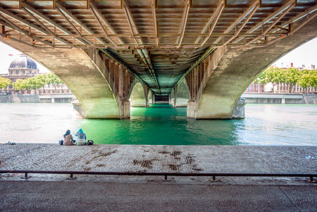 LYON, FRANCE - JUNE 5: unrecognizable women sitting under the bridge near river on embankment of Lyon, France, june 2015のeditorial素材
