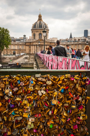 PARIS, FRANCE - JUNE 9: Padlocks on the fence and people passing Pont de Arts bridge in Paris on June 9, 2015のeditorial素材