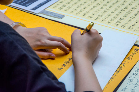 Woman writing chinese calligraphy with pencil on the paperの写真素材