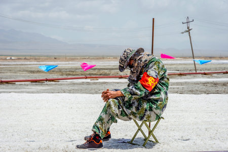 CHAKAZHEN CHINA - JUNE 23: Security guard sleeping on a chair next to Chaqia salt lake Qinghai. June 2016のeditorial素材