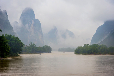 Li river with misty clouds and fog surrounded by famous karst mountains Guangxi Zhuang Chinaの写真素材