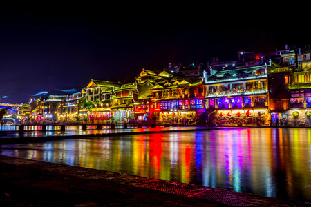 FENGHUANG CHINA - JUNE 14: Illuminated traditional Chinese architecture buildings in city's downtown by the river bank at night. June 2016のeditorial素材