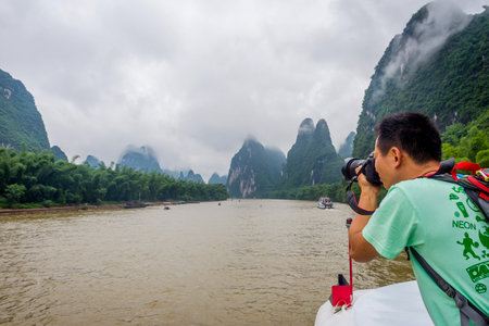 GUILIN CHINA - JUNE 12: Photographer taking photos from the ship cruising the Li river surrounded by famous karst mountains. June 2016のeditorial素材