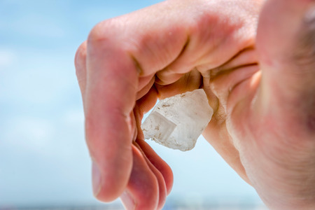 Holding big salt crystal in hand against blue skyの写真素材