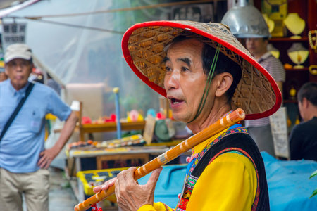 YANGSHUO CHINA - JUNE 12: Street artist playing wooden flute in Yangshuo downtown Guilin region. June 2016のeditorial素材
