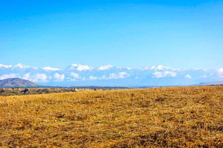 River, green meadow, golden fields and mountains with snow peaks, amazing landscapes of Azerbaijanの写真素材
