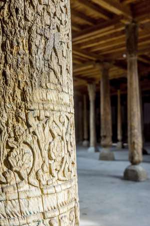 Sun rays shining through many carved wooden pillars in the old madrassa in Khiva, Uzbekistanの写真素材
