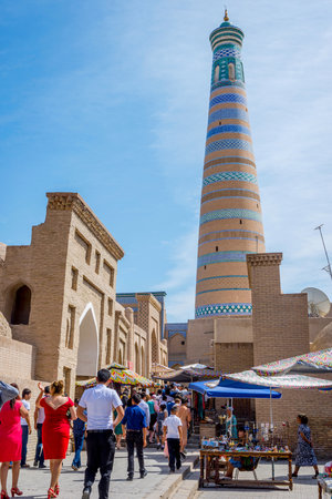 KHIVA, UZBEKISTAN - SEPTEMBER 7: People walking in narrow street in Khiva old town and minaret behind. September 2016のeditorial素材