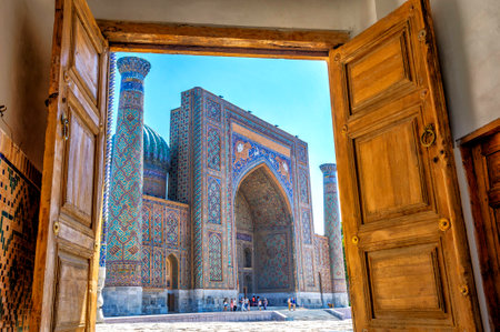 SAMARKAND, UZBEKISTAN - AUGUST 28: View to Sher Dor Madrasah thru the carved wooden door of Registan - landmark of Samarkand. HDR photo. August 2016のeditorial素材