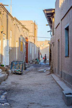 KHIVA, UZBEKISTAN - SEPTEMBER 6: Woman carrying bucket in the street in Khiva old town. September 2016のeditorial素材