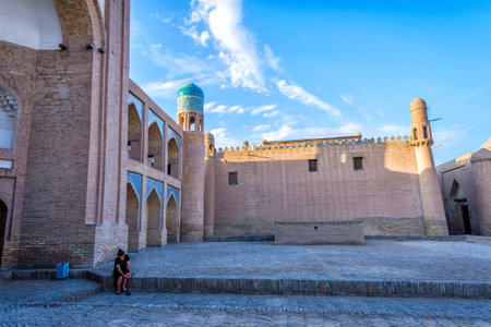 KHIVA, UZBEKISTAN - SEPTEMBER 6: Woman sitting in front of old madrassa in Khiva old town. September 2016のeditorial素材