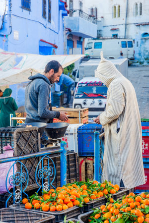 Chefchaouen, MOROCCO - DECEMBER 8: Man picking oranges at the local market in Chefchaouen. December 2016のeditorial素材