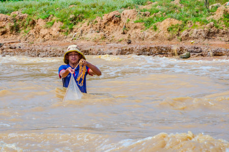 TONLE SAP, CAMBODIA - APRIL 8: Young man fishing with a net from the river close to Tonle Sap floating village. April 2017のeditorial素材