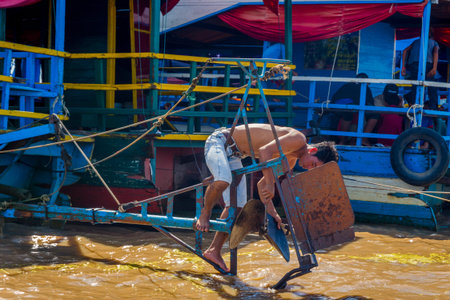 TONLE SAP, CAMBODIA - APRIL 8: Guy repairing the motor of the boat in Tonle Sap floating village. April 2017のeditorial素材