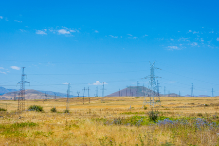 Electric wires and installation over the dry summer fields and meadows, Armeniaの写真素材