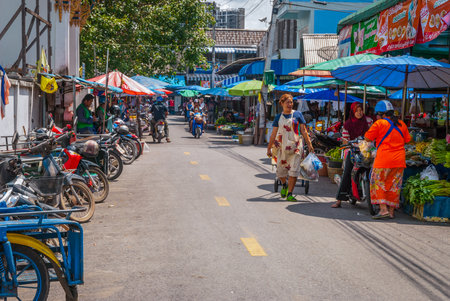 Hat Yai, Thailand - Oct 2015: People on motorbikes and local stands selling local produce like fruits and vegetables in local market.のeditorial素材