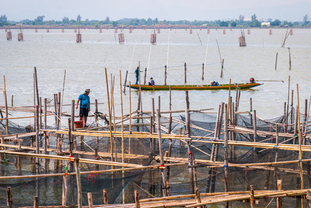 Songkhla, Thailand - Oct 2015: Fisherman walking on the platform between fishing nets at Songkhla Lake, Thailandのeditorial素材