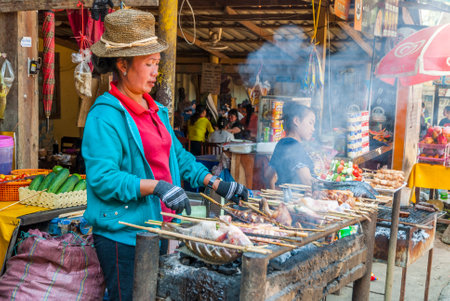 Luang Prabang, Laos - Feb 2016: Women barbecuing fish and meet at the restaurant next to Kuang Si Waterfall, Laosのeditorial素材