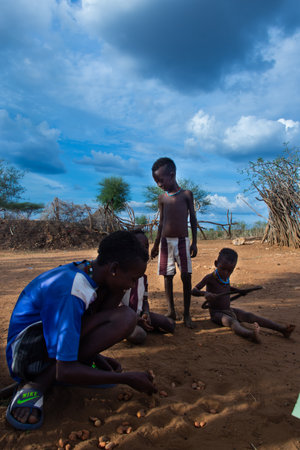 Turmi, Ethiopia - Nov 2018: Hamer tribe guys playing a game with stones in the ground. Omo valleyのeditorial素材