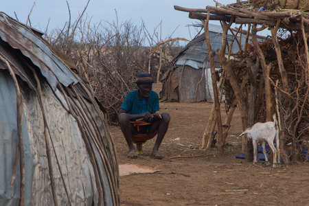 Omorate, Ethiopia - Nov 2018: Dasanech tribe man sitting on the mini chair. Omo valleyのeditorial素材